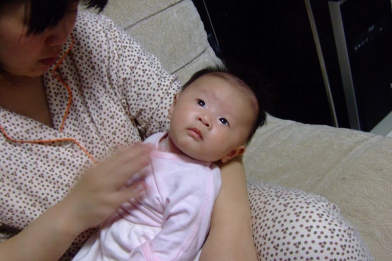 an asian woman sitting next to her baby