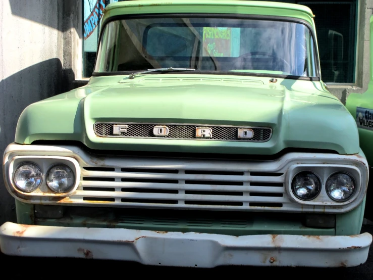 an old green truck sits parked outside