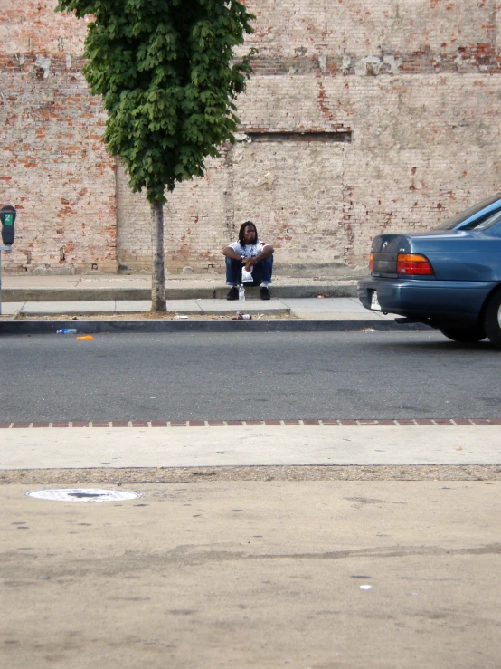 a person with a phone sitting on the side of the road
