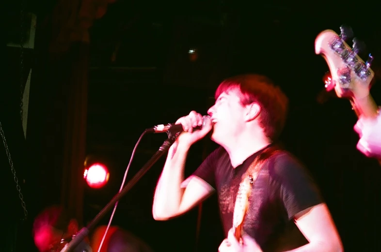 a man holding a guitar and singing into microphone