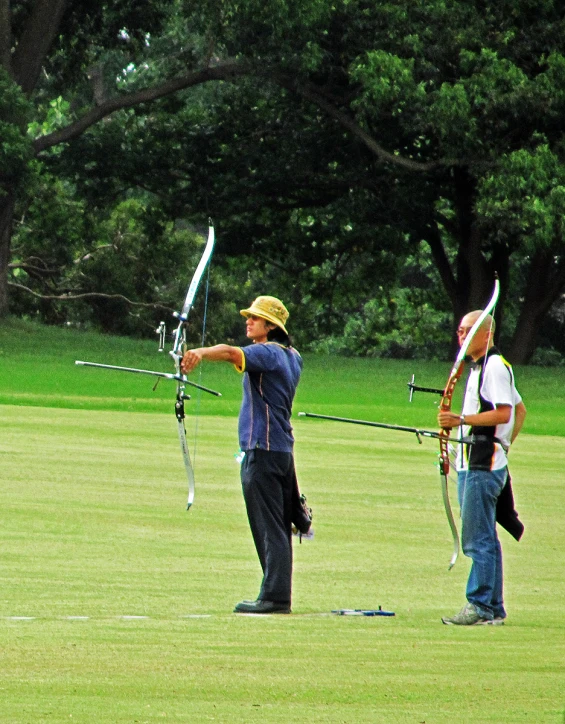 two men on grass with a bow and arrows