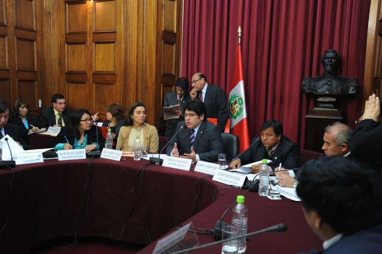 a group of people sitting at a table and in front of a microphone with papers all over them