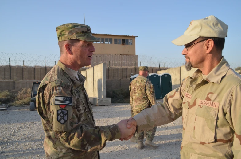 a soldier shakes hands with an armed man in front of other soldiers