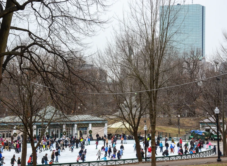 several people walking across snow covered ground in front of a train station