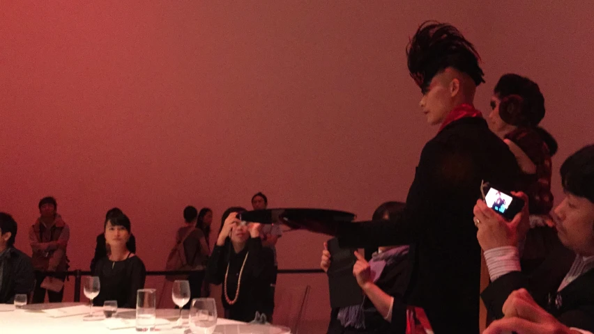 woman with wine glass looking to camera while others sit at a round table