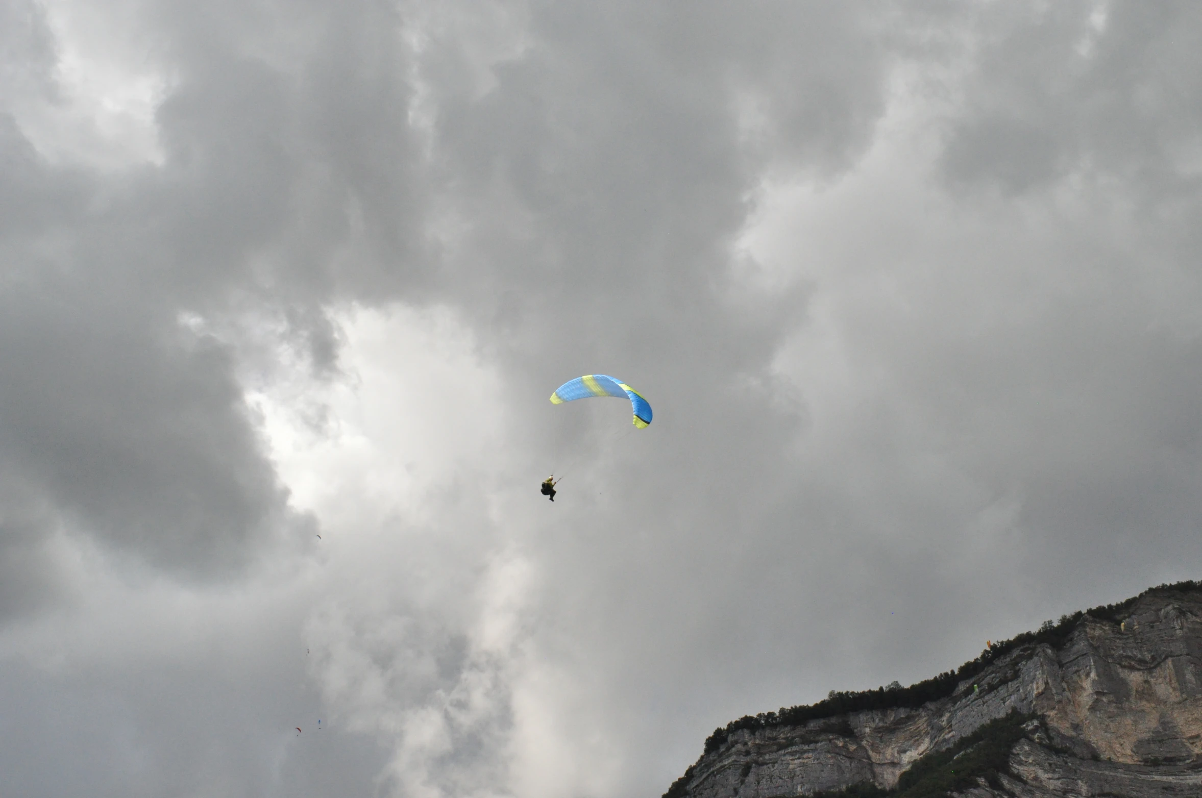 parasailers are seen flying against cloudy skies