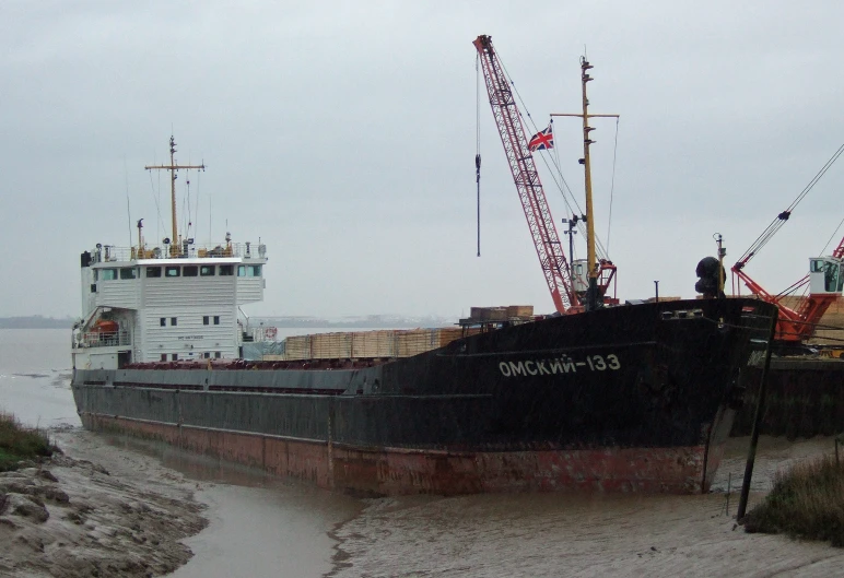 a large boat sits at a dock next to a barge