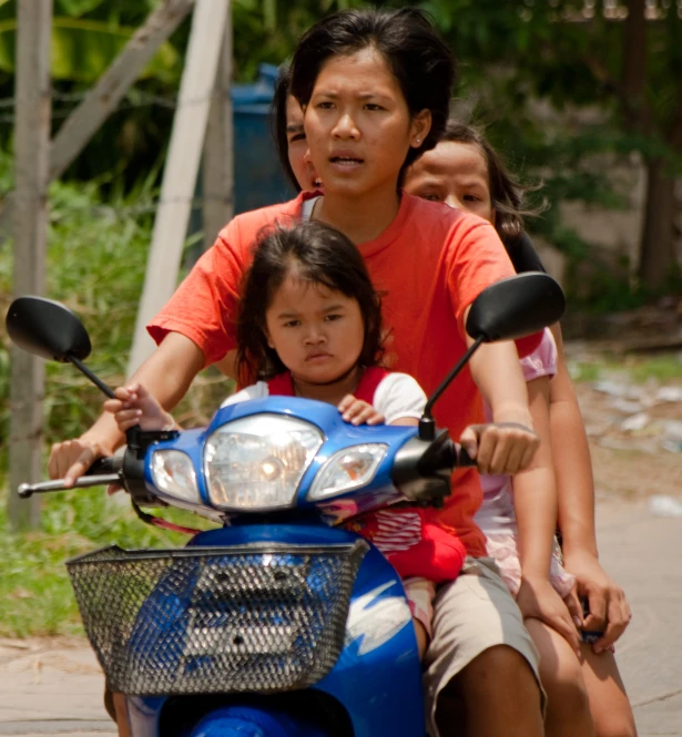 an adult and two children on a moped