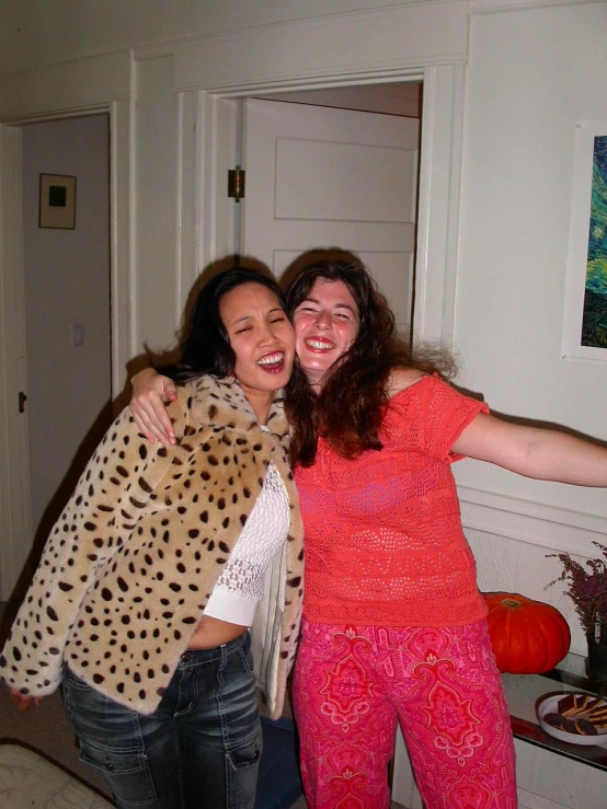 two woman pose together in front of an empty room