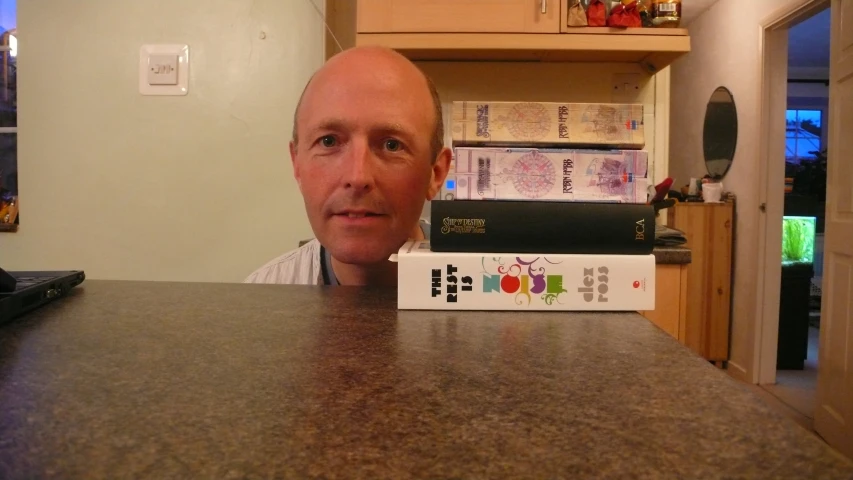 a bald headed man sitting at a counter with an object in front of him