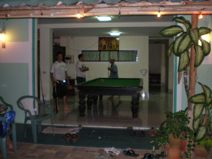 a group of guys standing around a pool table in a living room
