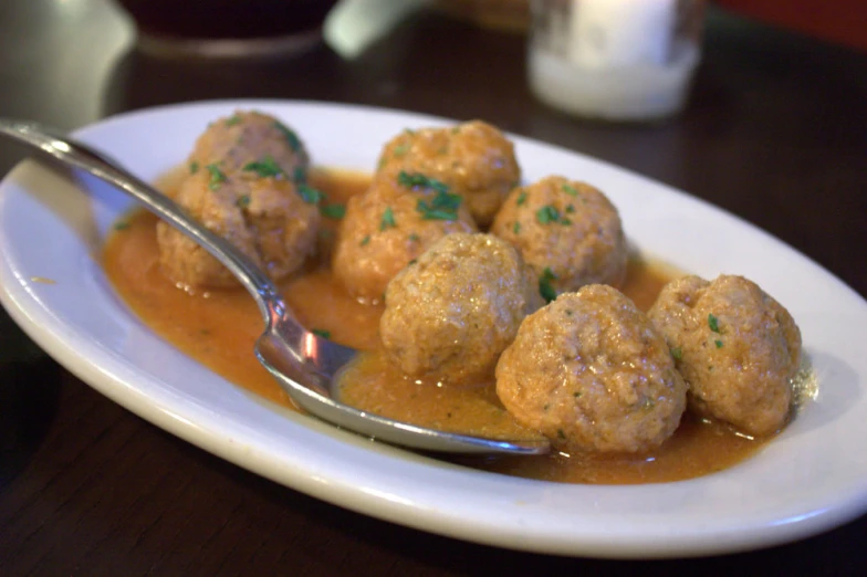 there is meatballs with sauce on a white plate