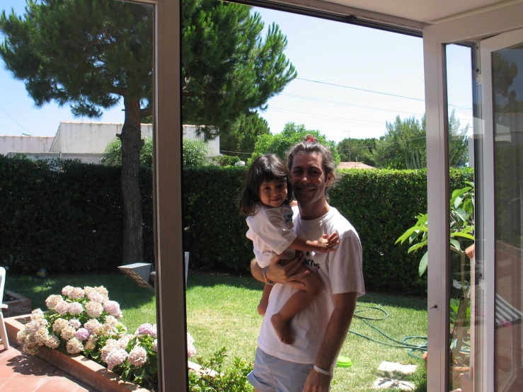 a man holds a small girl outside of a house