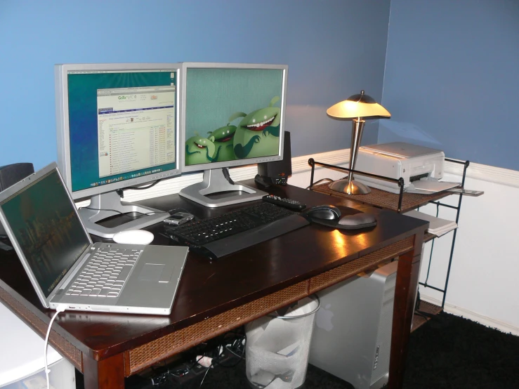 a desk with two monitors, laptop and desktop