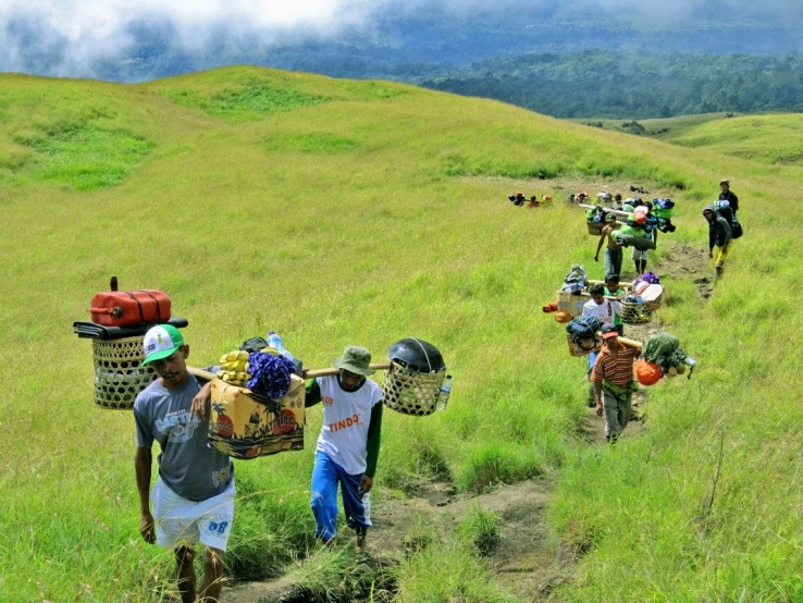 a group of people are walking down a hill carrying things