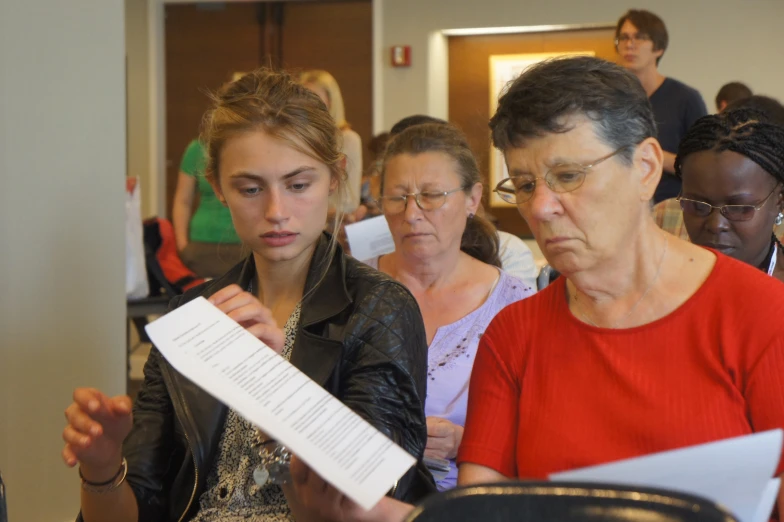 two women are checking out their papers as a man looks on