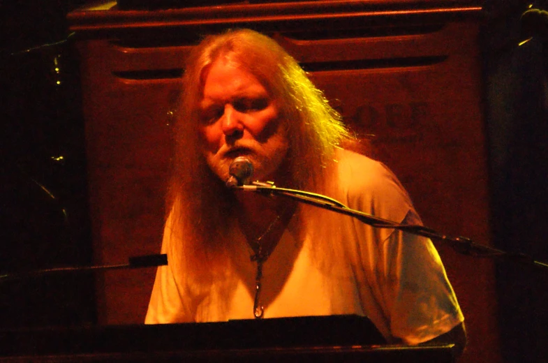 an old man with long hair standing at a microphone