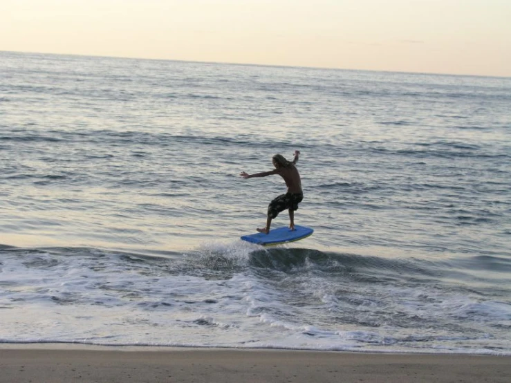 there is a man on the beach doing a jump on his surfboard