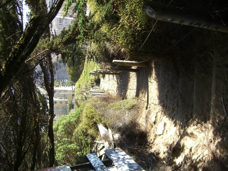 a view of a stone fence next to an alley with picnic tables