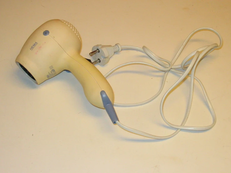 a hair dryer with a white cord laying across it