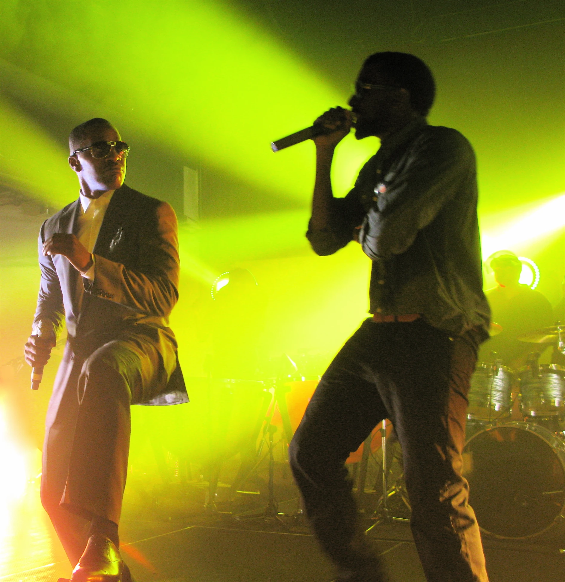 two men singing on stage and lights above them