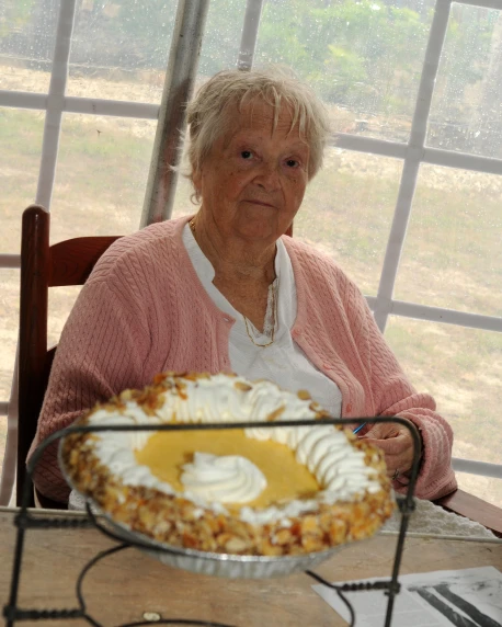 a woman is sitting behind a pie on a table