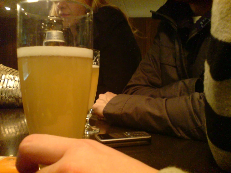 the man holds a glass of beer next to a cell phone