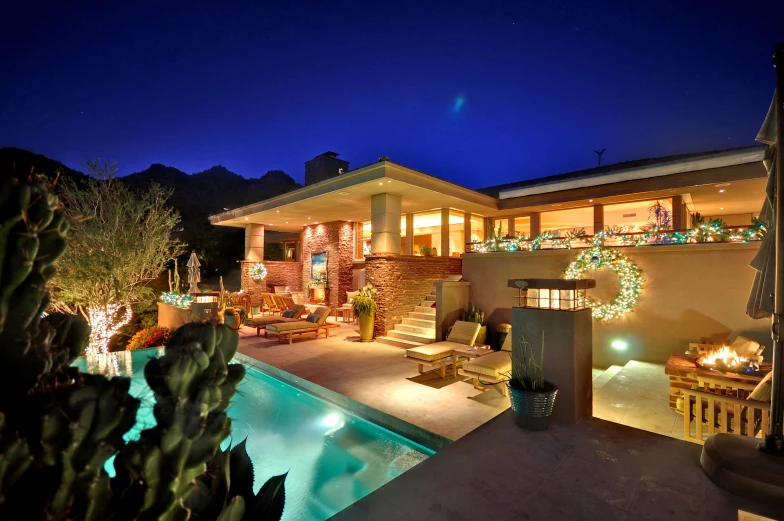 a house decorated with lights at night and lit up with cactus