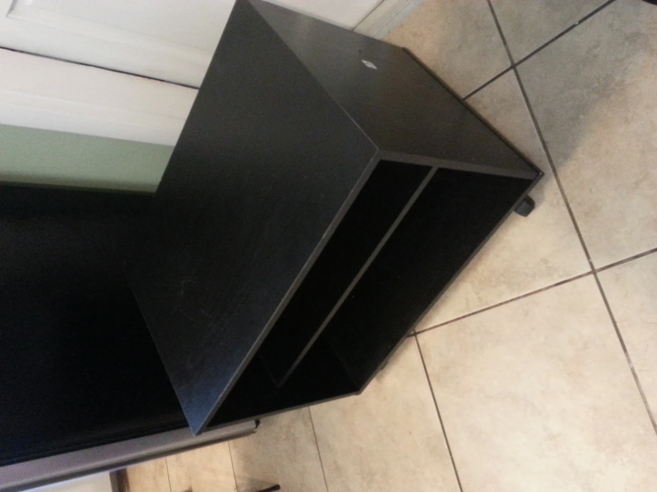 a black shelf sitting on a floor near a cabinet