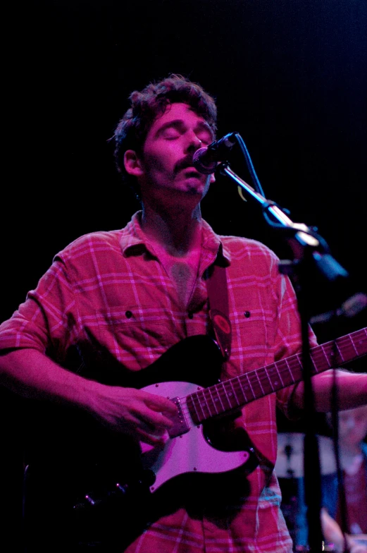 a man singing into a microphone and playing a guitar