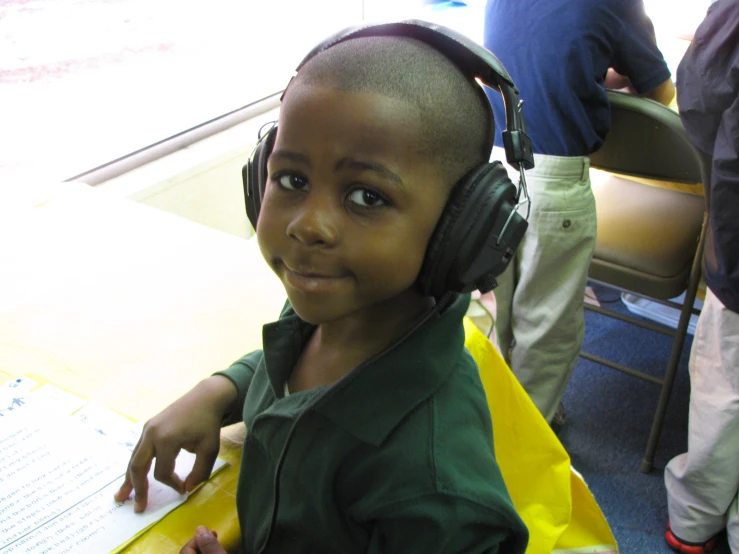 a little boy sitting in front of headphones at a table