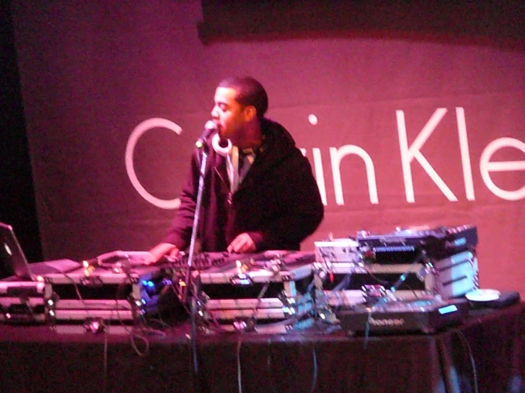 a man standing in front of a laptop computer next to a dj set