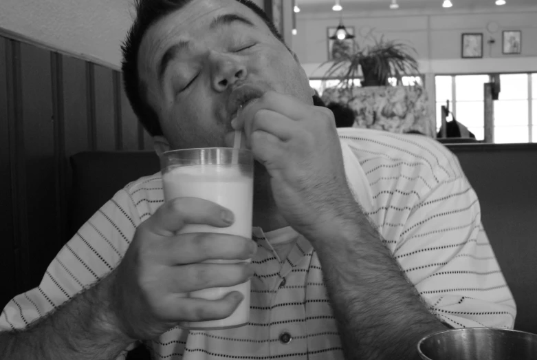 a man drinking milk from a glass in a restaurant