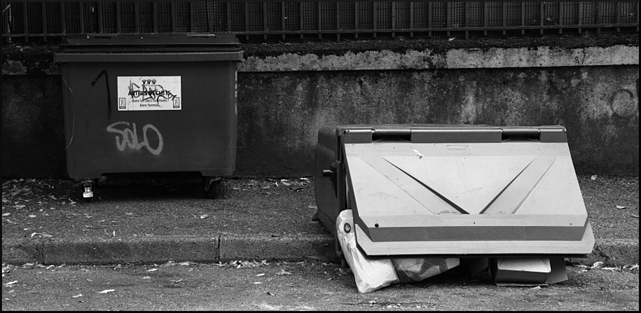 two garbage cans sit by a wall and the ground