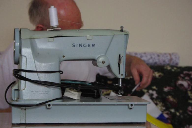 an older man is sewing with an old singer sewing machine