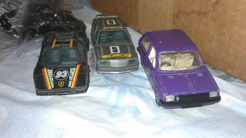 three toys racing cars one purple, the other black