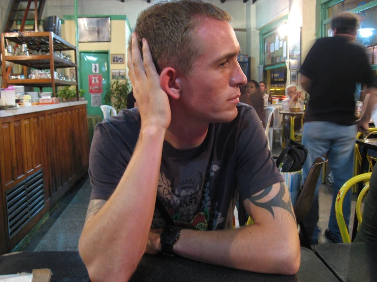 a man sits at the table while talking on his cellphone