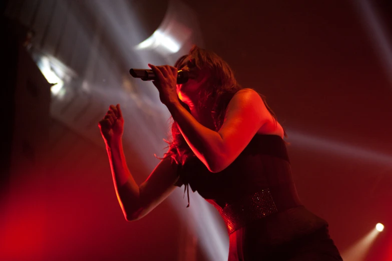 a woman in black dress singing into microphone