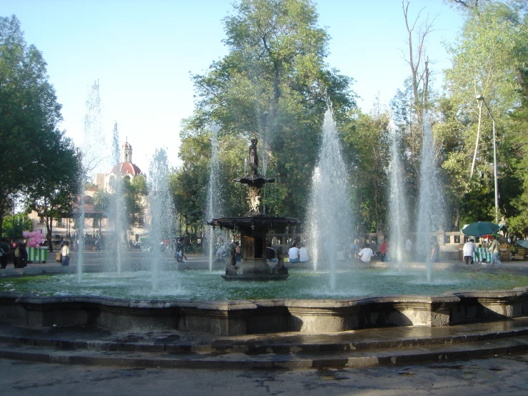 the water fountain is surrounded by people and trees