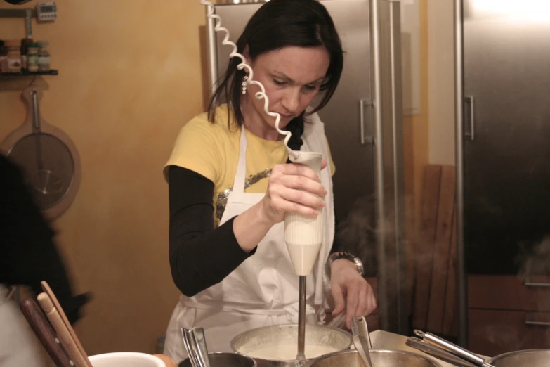 a woman standing in a kitchen next to a mixing bowl