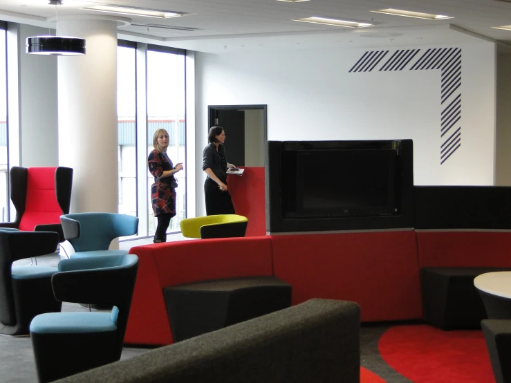 two women standing in front of a tv in an office