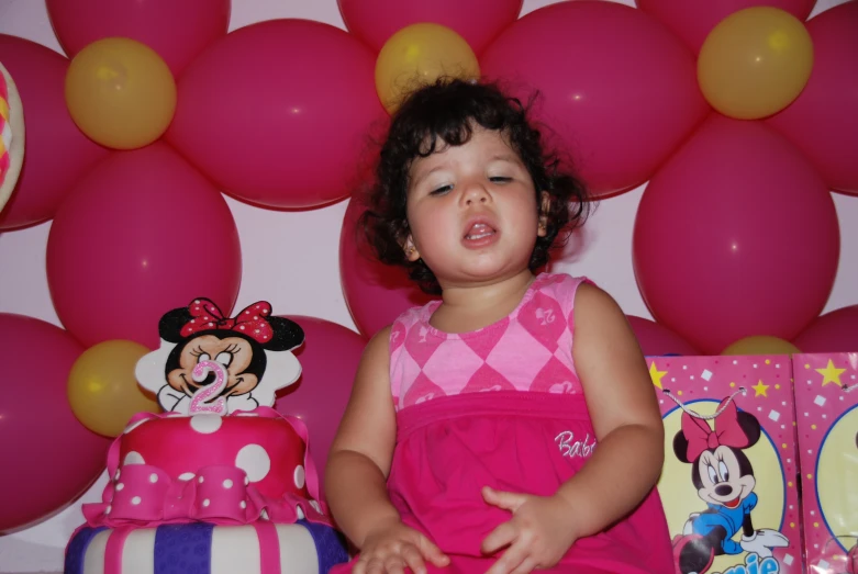 the girl is sitting in front of her birthday cake