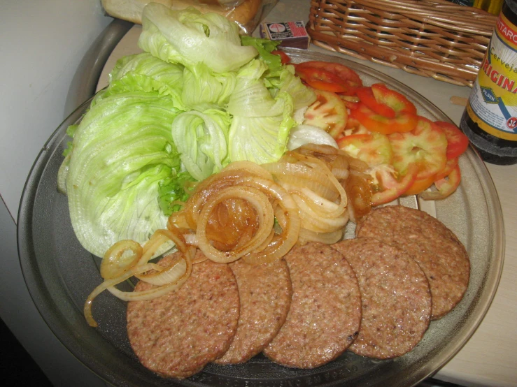 meat sausage, tomatoes, onion and lettuce on a clear plate