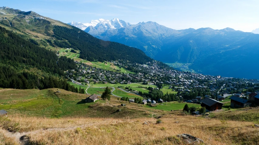 the mountains range over a town surrounded by lush green hills