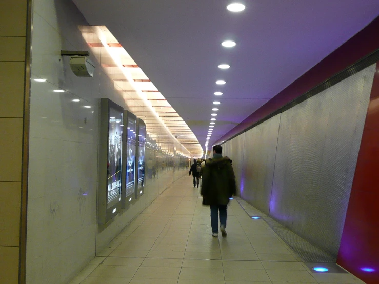 people walk down a hallway that is lit up with red lights