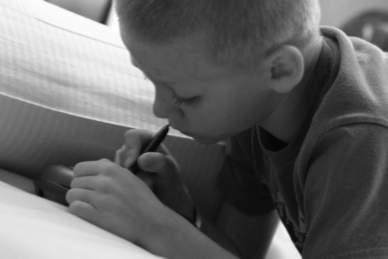 a small boy is writing with a pen