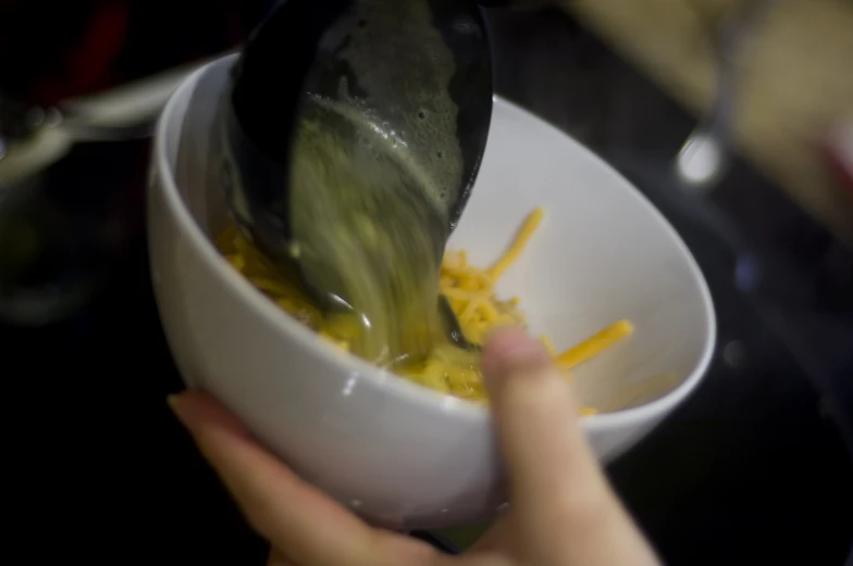 the hand holds a spoon that is inside a bowl