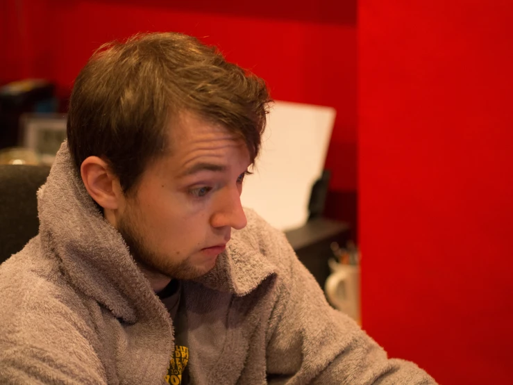 a man in grey coat sitting down and using his phone