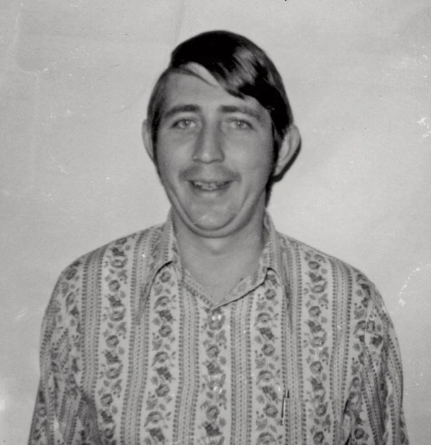 man in flowered shirt smiling for the camera
