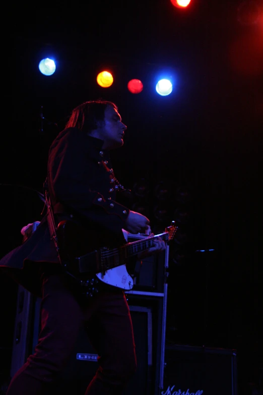 man standing on stage playing the guitar with his legs on a soundboard